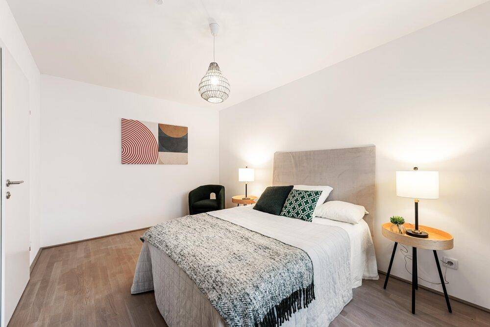 Modern eingerichtetes Schlafzimmer mit hellem Holzboden und stilvollen Nachttischen.