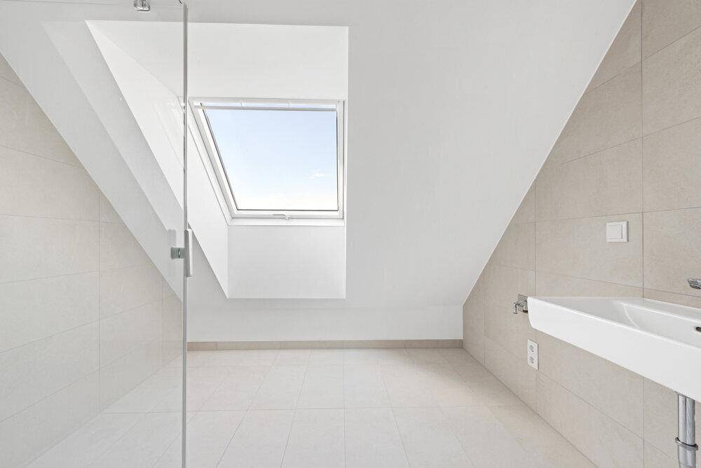 Modernes Badezimmer mit Dachfenster, Fliesenboden und minimalistischem Design.