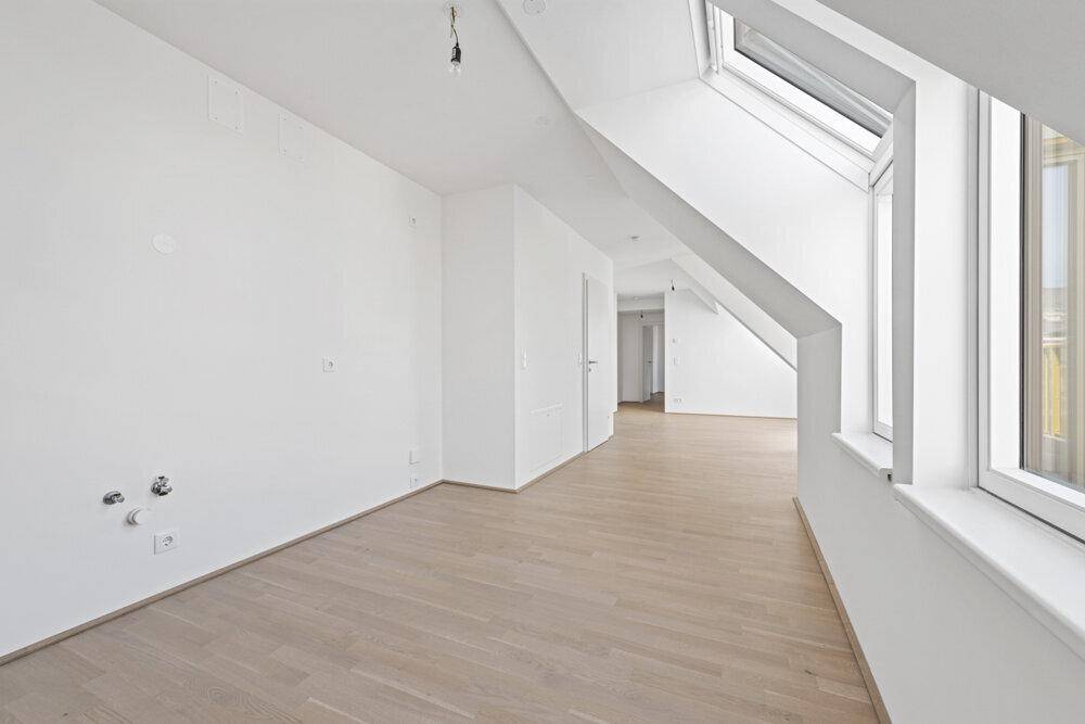 Heller Raum mit Holzboden, Dachfenstern und Anschlüssen für eine Küche oder Bad.