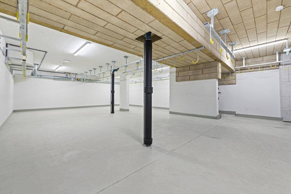 Geräumiger Kellerraum mit Betonboden und sichtbaren Installationen.