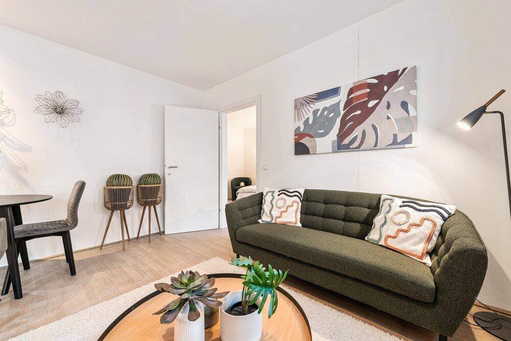 Gemütliches Wohnzimmer mit modernem Sofa, Couchtisch und dekorativen Pflanzen.