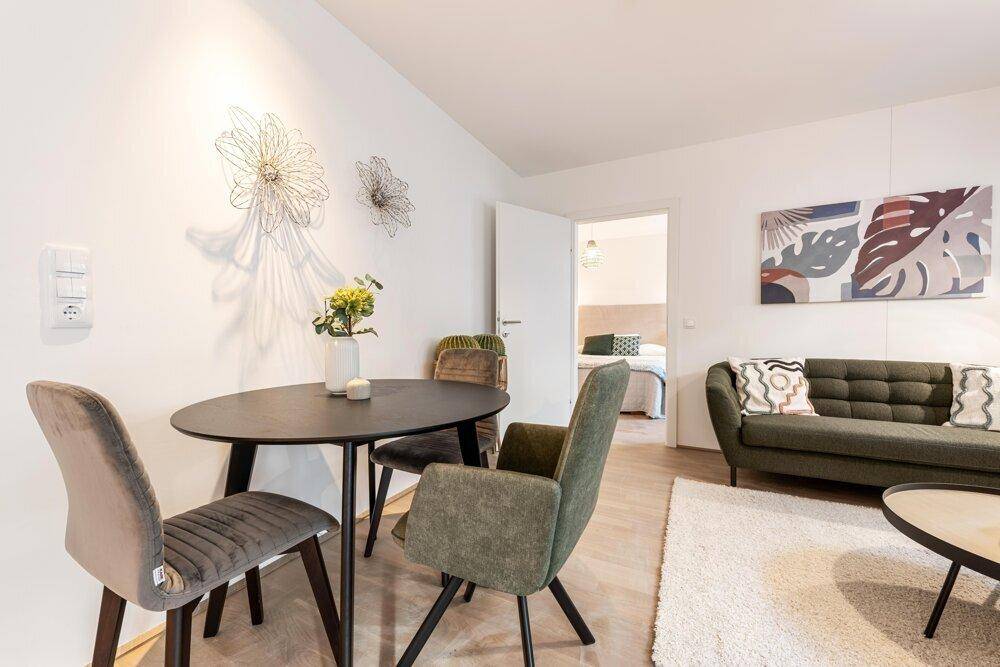 Gemütlicher Wohnbereich mit Esstisch, Sofa und moderner Wanddekoration.