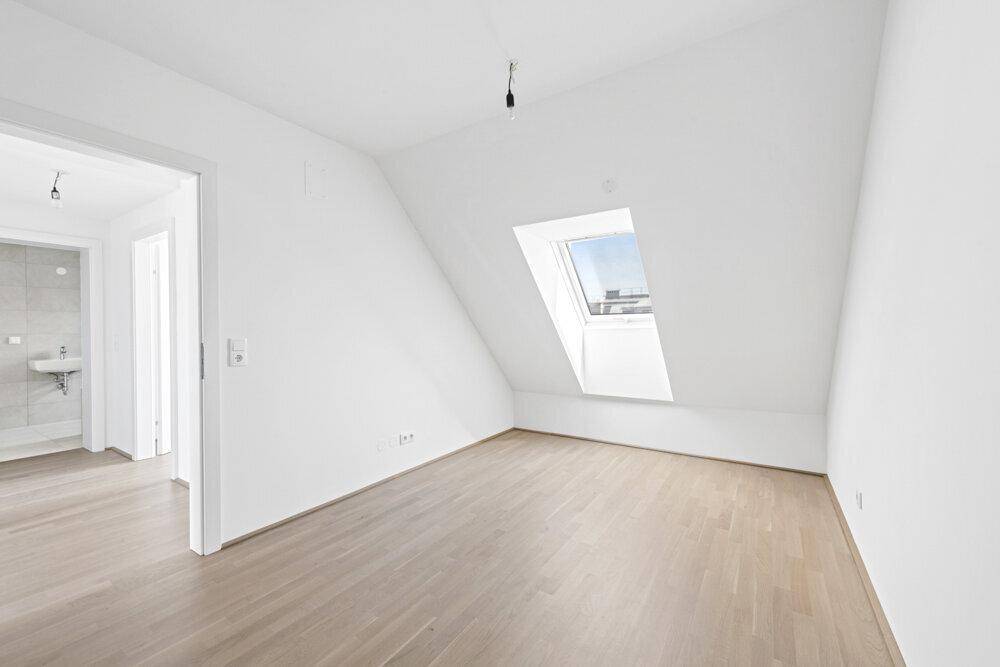 Geräumiges Schlafzimmer mit Dachfenster und Zugang zu einem angrenzenden Badezimmer.