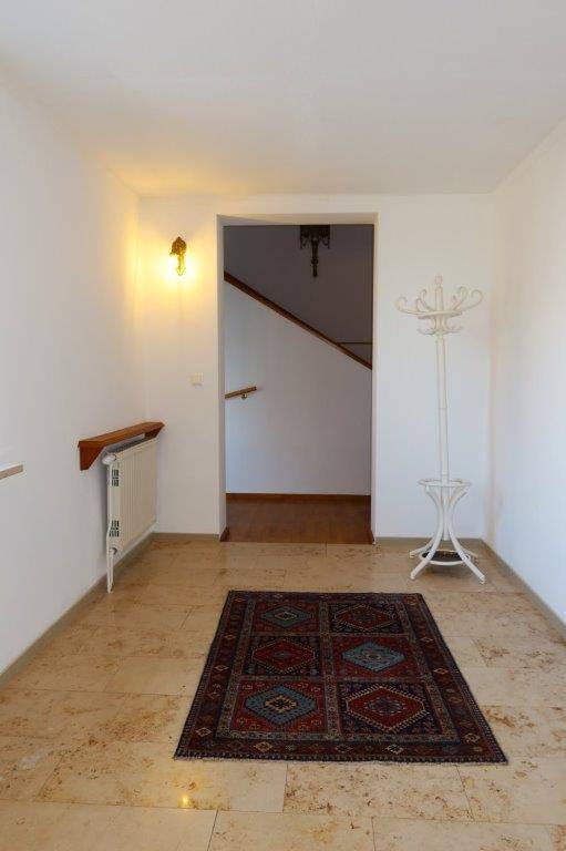 Heller Eingangsbereich mit Fliesenboden und Garderobe, Blick zur Treppe.