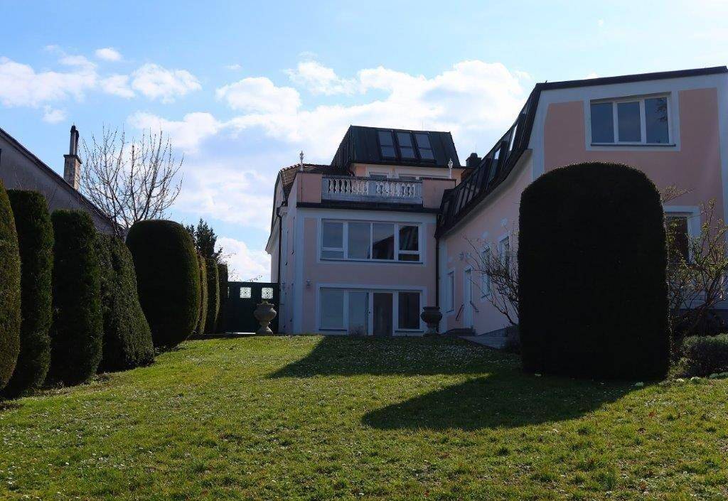 Gepflegter Gartenbereich mit Rasenfläche und hohen Hecken vor dem Haus.