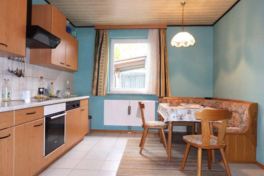 Gemütliche Küche mit Holzschränken, blauen Wänden und einem Essbereich am Fenster.
