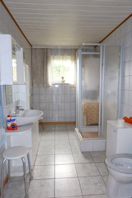 Funktionales Badezimmer mit Duschkabine, Waschbecken und Fenster für Tageslicht.