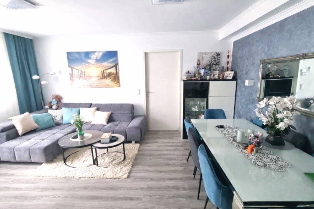 Geräumiger Wohn-Essbereich mit grauem Sofa, Esstisch und moderner Dekoration.