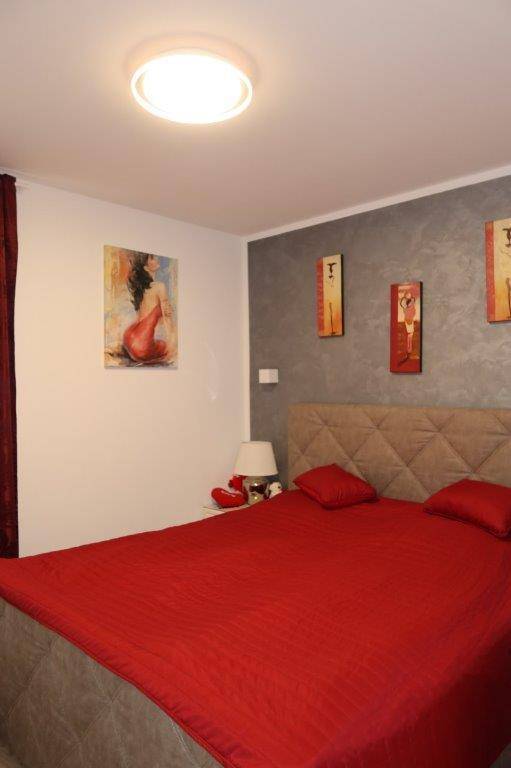 Schlafzimmer mit großem Bett, roter Bettwäsche und einer Akzentwand in Grau.