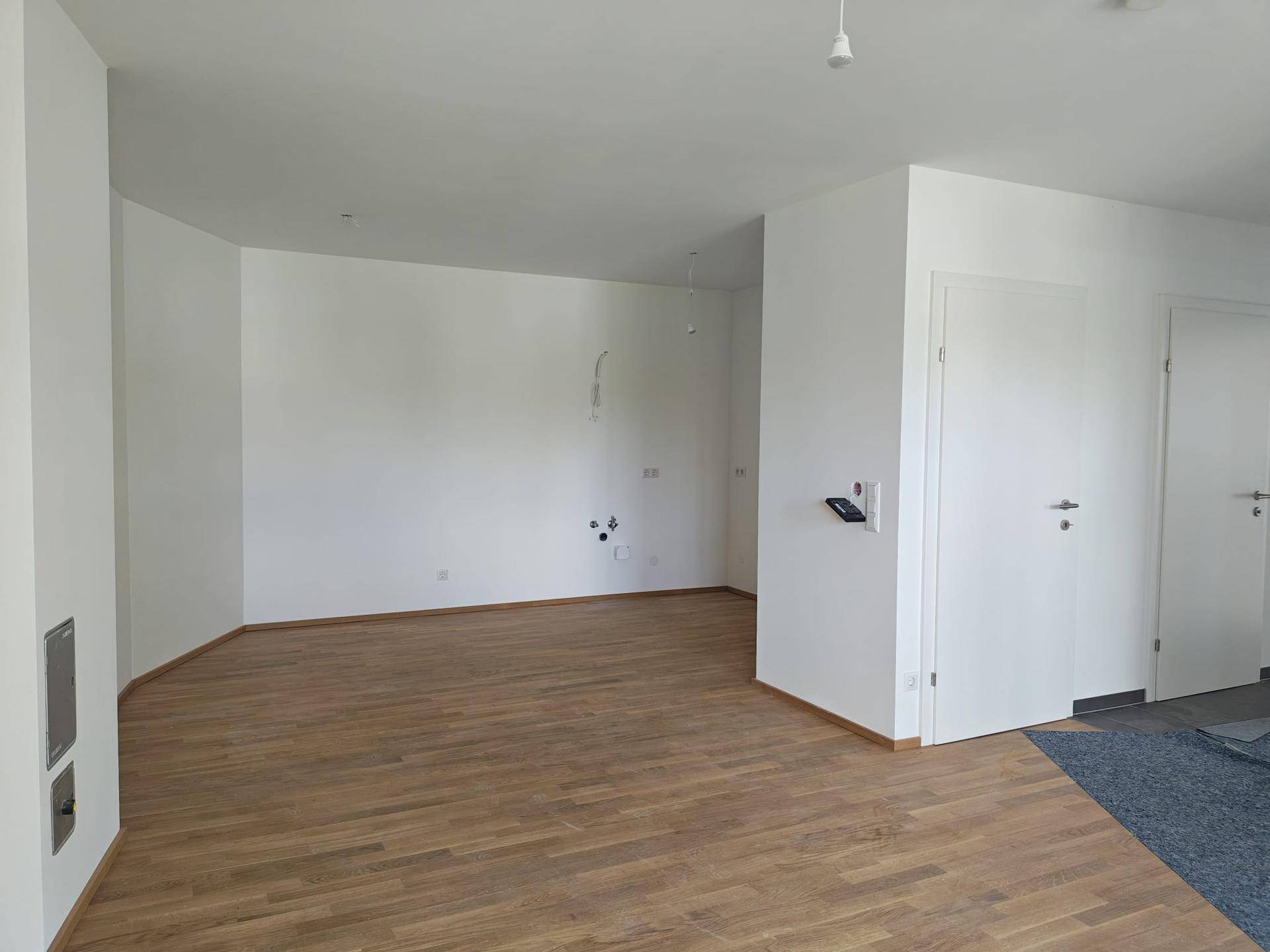 Heller, leerer Raum mit Eichenparkett und weißen Wänden, bereit zur individuellen Gestaltung.