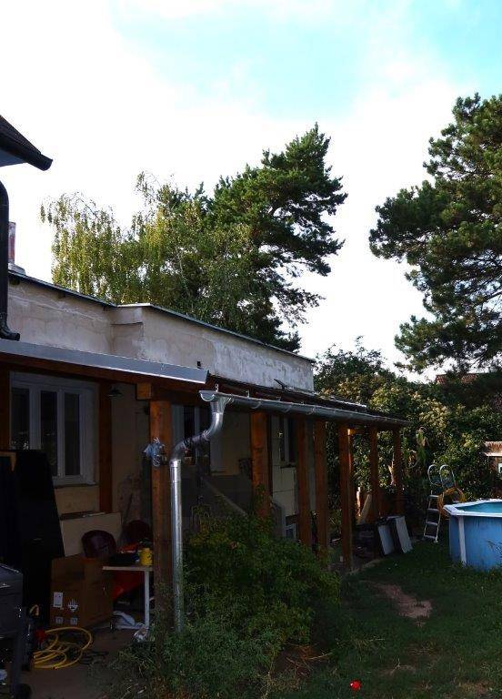 Überdachte Terrasse mit Holzbalken, einem kleinen Pool und Blick ins Grüne.