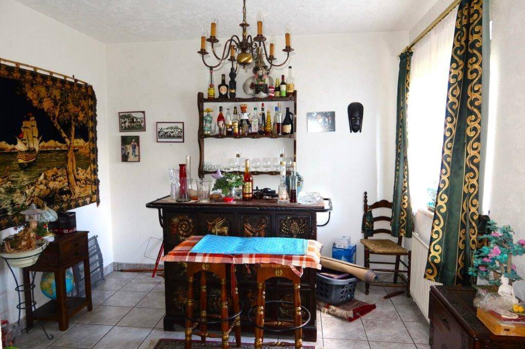 Gemütlicher Wohnbereich mit einer Hausbar, Fliesenboden und dekorativen Vorhängen am Fenster.