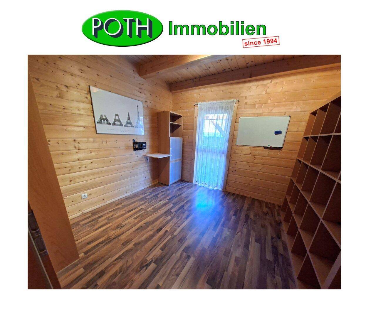 Arbeitszimmer mit Holzwänden, Laminatboden und Regalen, ideal für Home-Office.