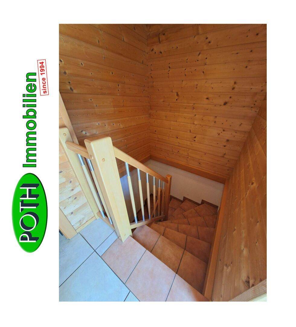 Treppenabgang in den Keller mit Holzgeländer und Fliesenboden, umgeben von Holzvertäfelung.