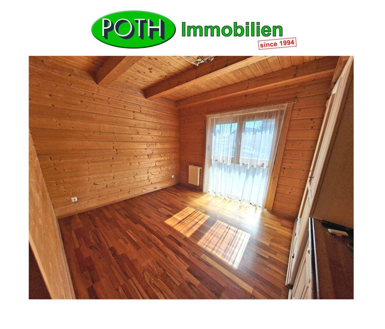 Schlafzimmer mit Holzwänden und -decke, Laminatboden und viel natürlichem Licht.
