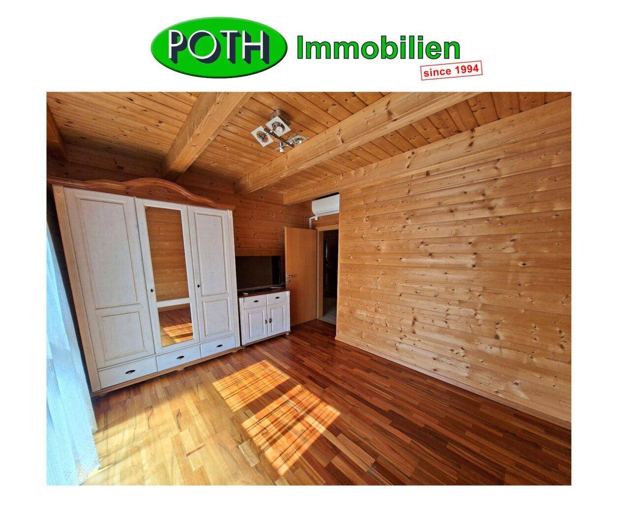 Geräumiges Schlafzimmer mit Holzwänden, Laminatboden und einem großen Kleiderschrank.