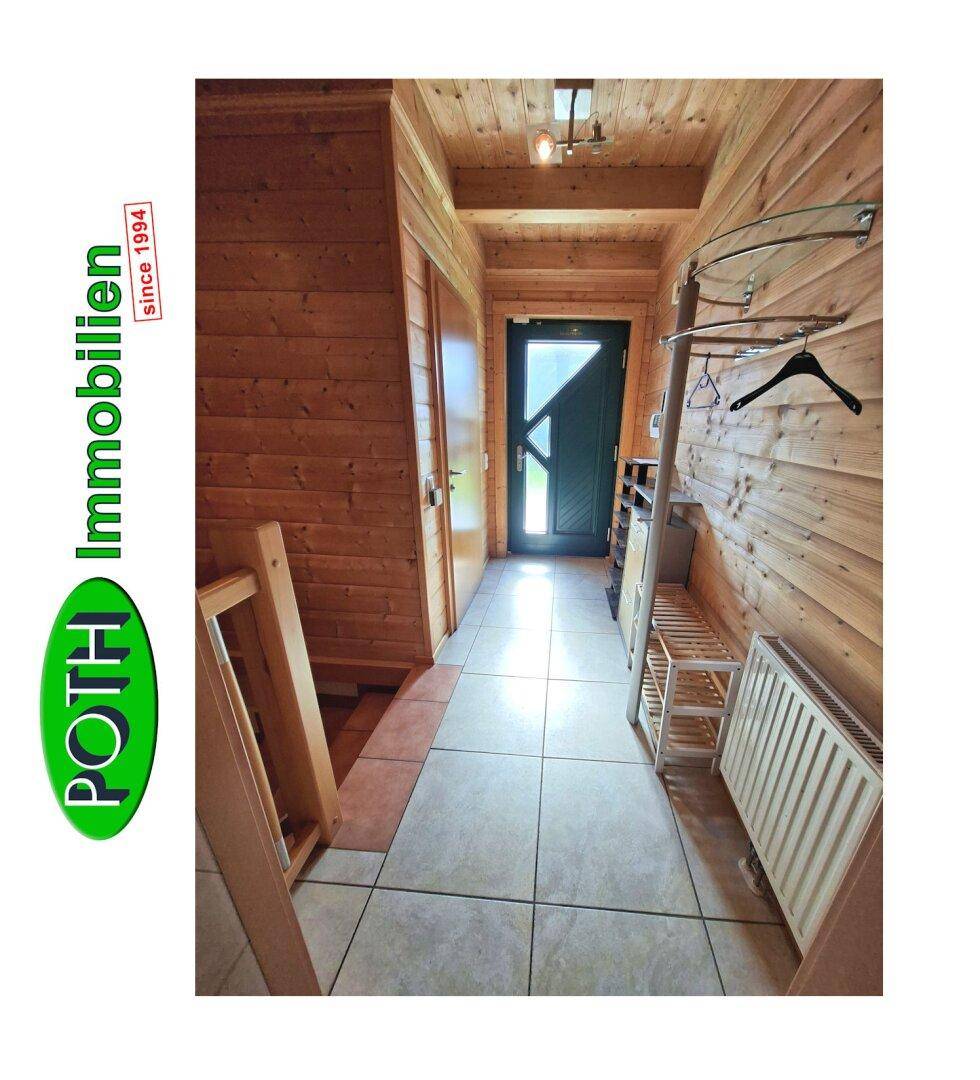 Gemütlicher Eingangsbereich mit Holzvertäfelung und Fliesenboden, der zur Haustür führt.