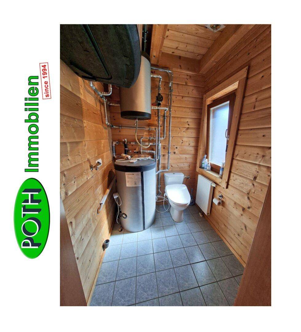 Technikraum mit Warmwasserboiler, Toilette und Holzvertäfelung an den Wänden.