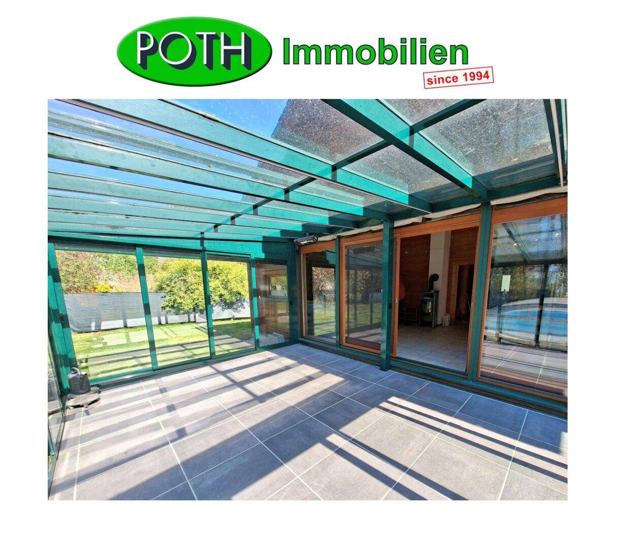 Lichtdurchfluteter Wintergarten mit Glasdach und Zugang zum Garten und Poolbereich.