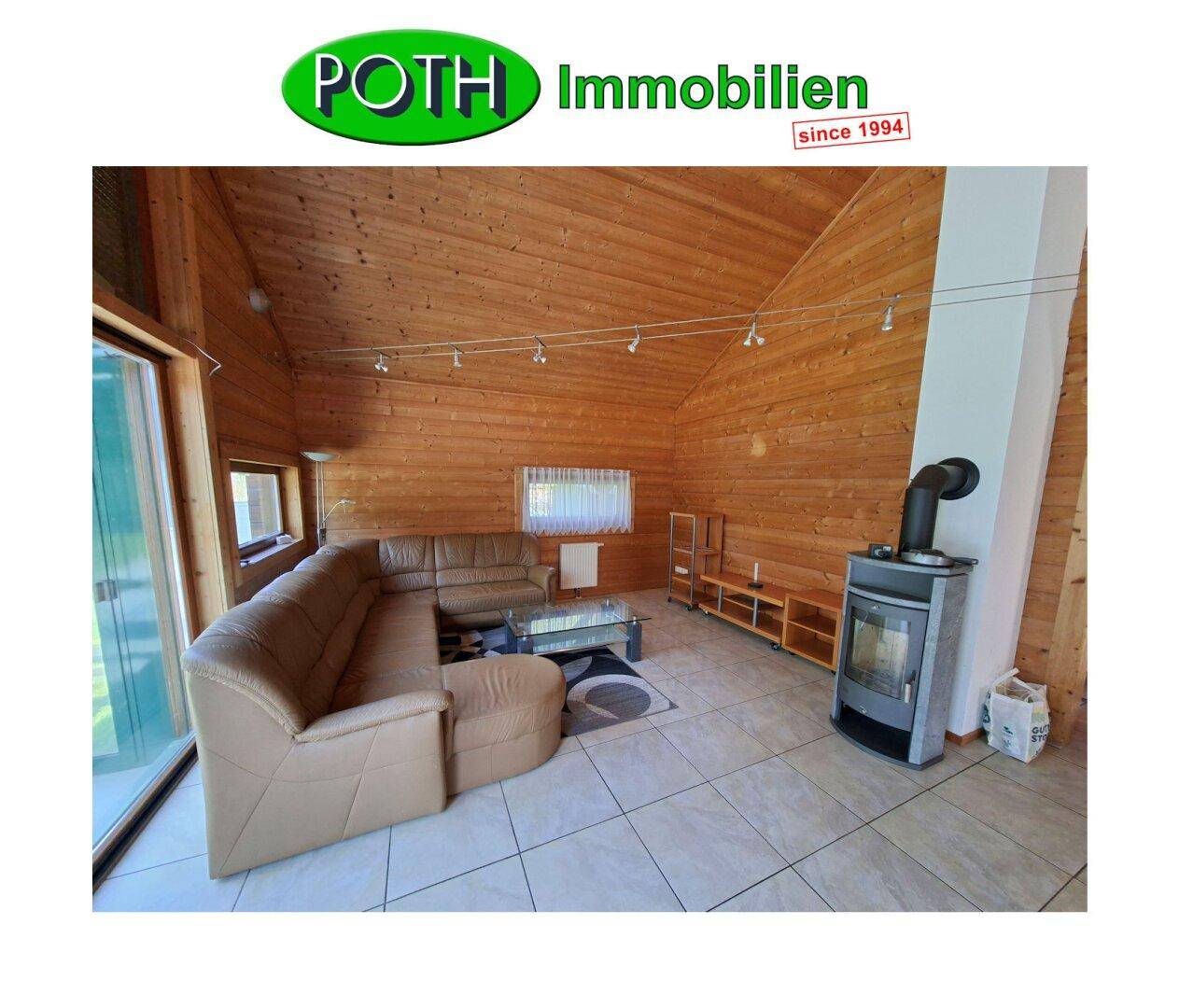 Gemütliches Wohnzimmer mit Holzwänden, Kaminofen und großem Ecksofa.