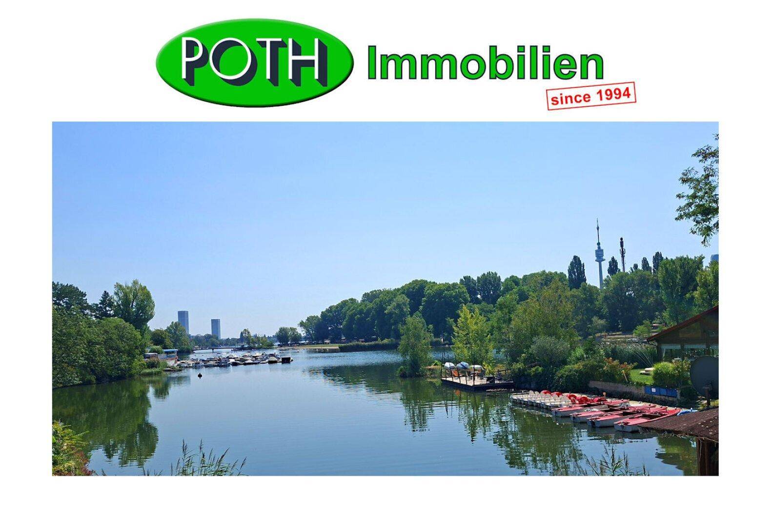 Panoramablick auf einen ruhigen Fluss oder See mit grünen Ufern, Booten und einer städtischen Silhouette am Horizont.