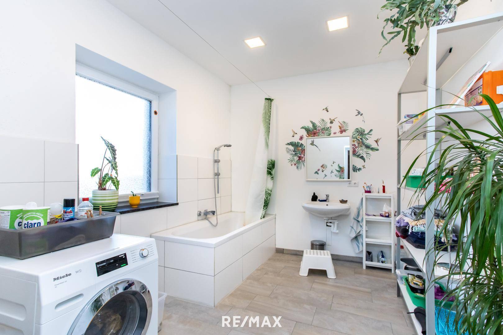 Helles Badezimmer mit Badewanne, Waschmaschine und Fenster für natürliche Belüftung.