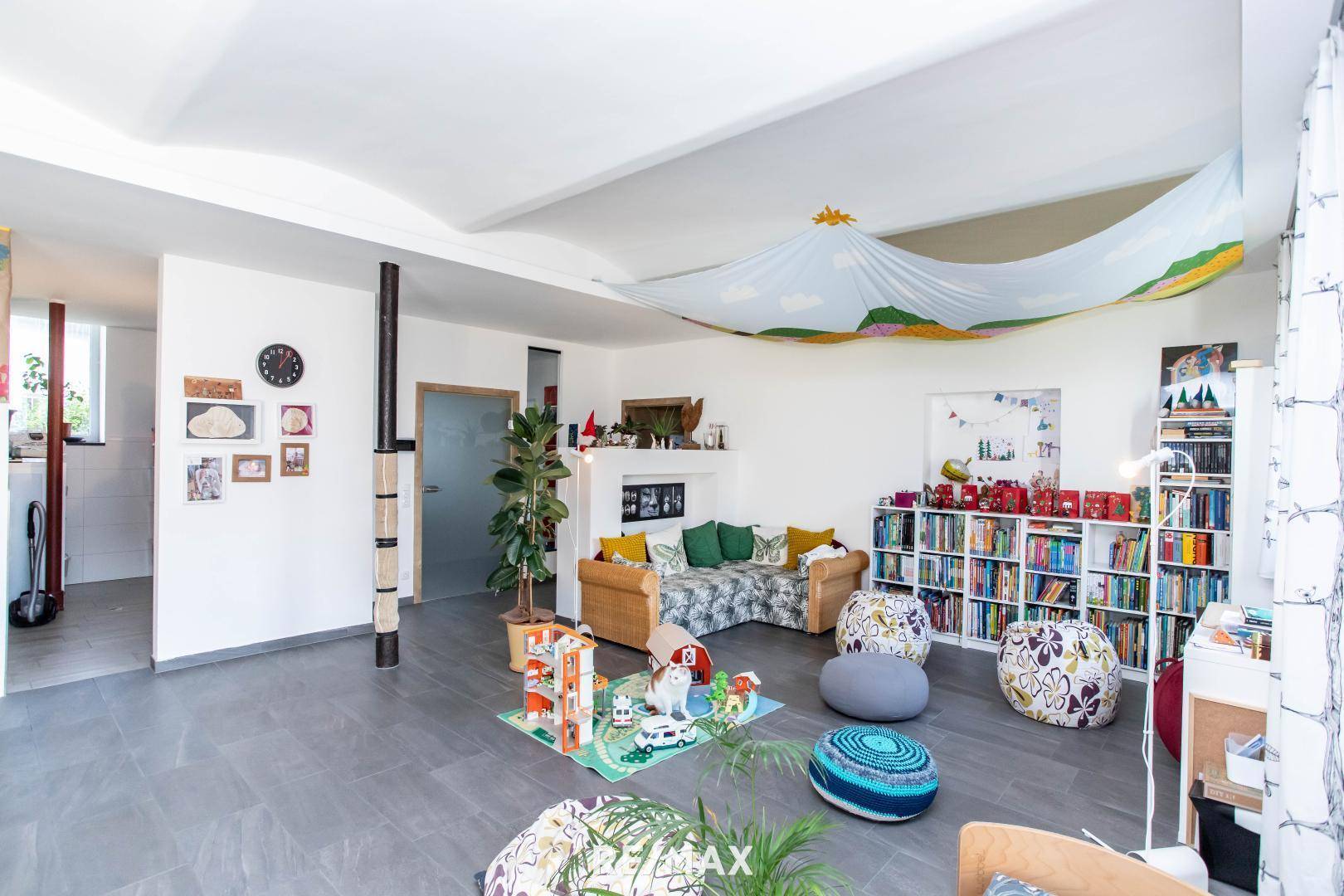 Gemütlicher Wohnbereich mit Bücherregalen, Spielzeug und dekorativer Deckenbespannung.