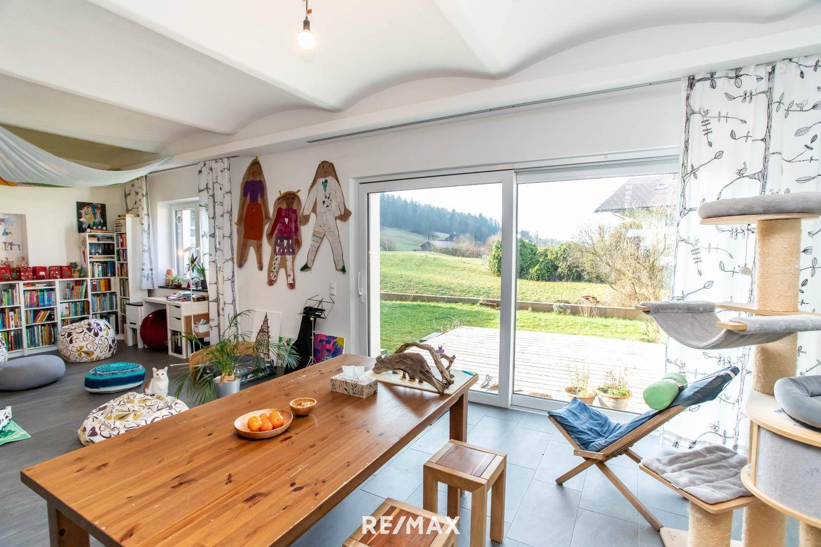 Heller Essbereich mit großem Holztisch und Schiebetür zum Garten mit grüner Aussicht.