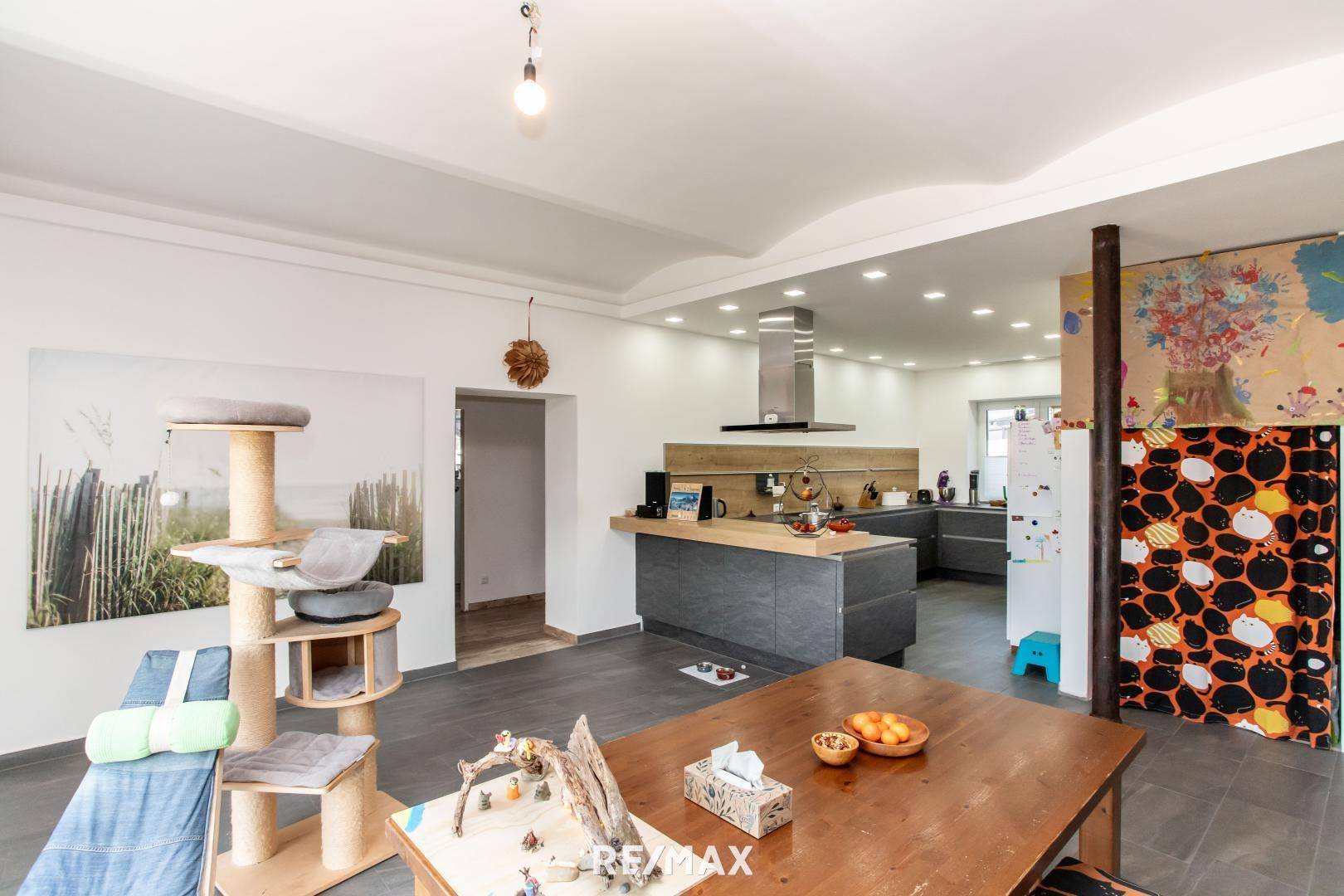 Moderne Küche mit Kochinsel und Dunstabzugshaube, offen zum Essbereich.