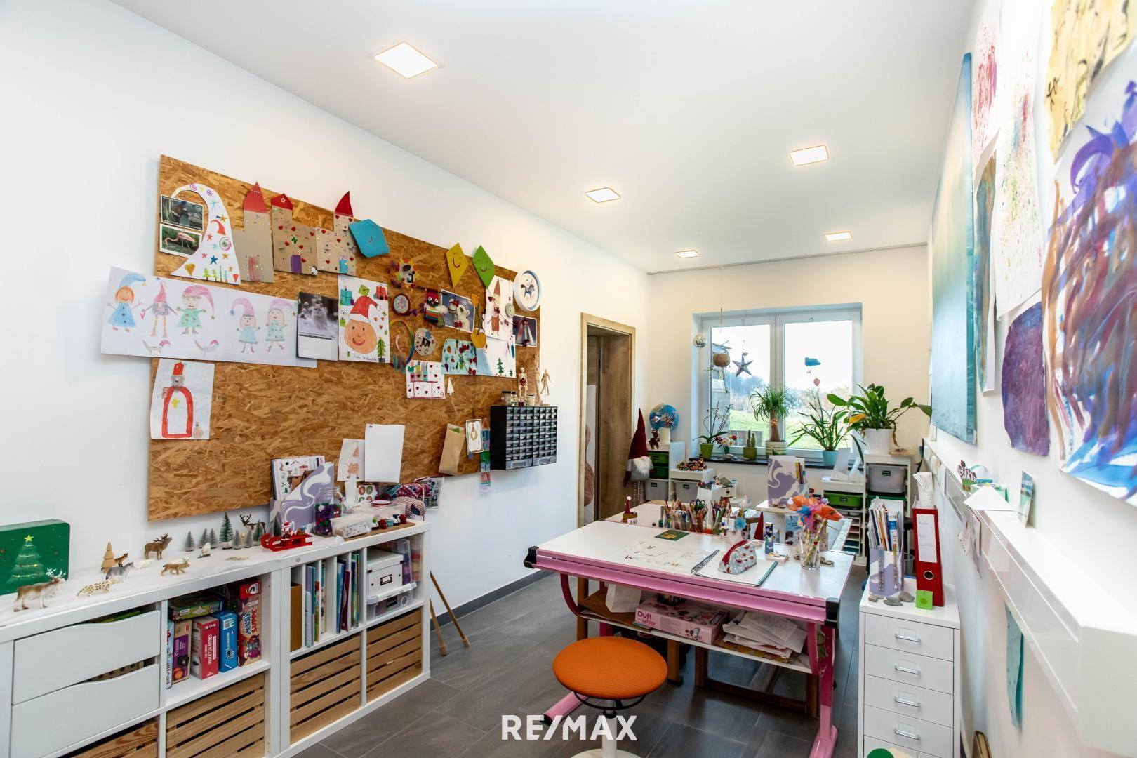 Kreativer Arbeits- oder Hobbyraum mit großem Fenster, viel Stauraum und Korkwand.