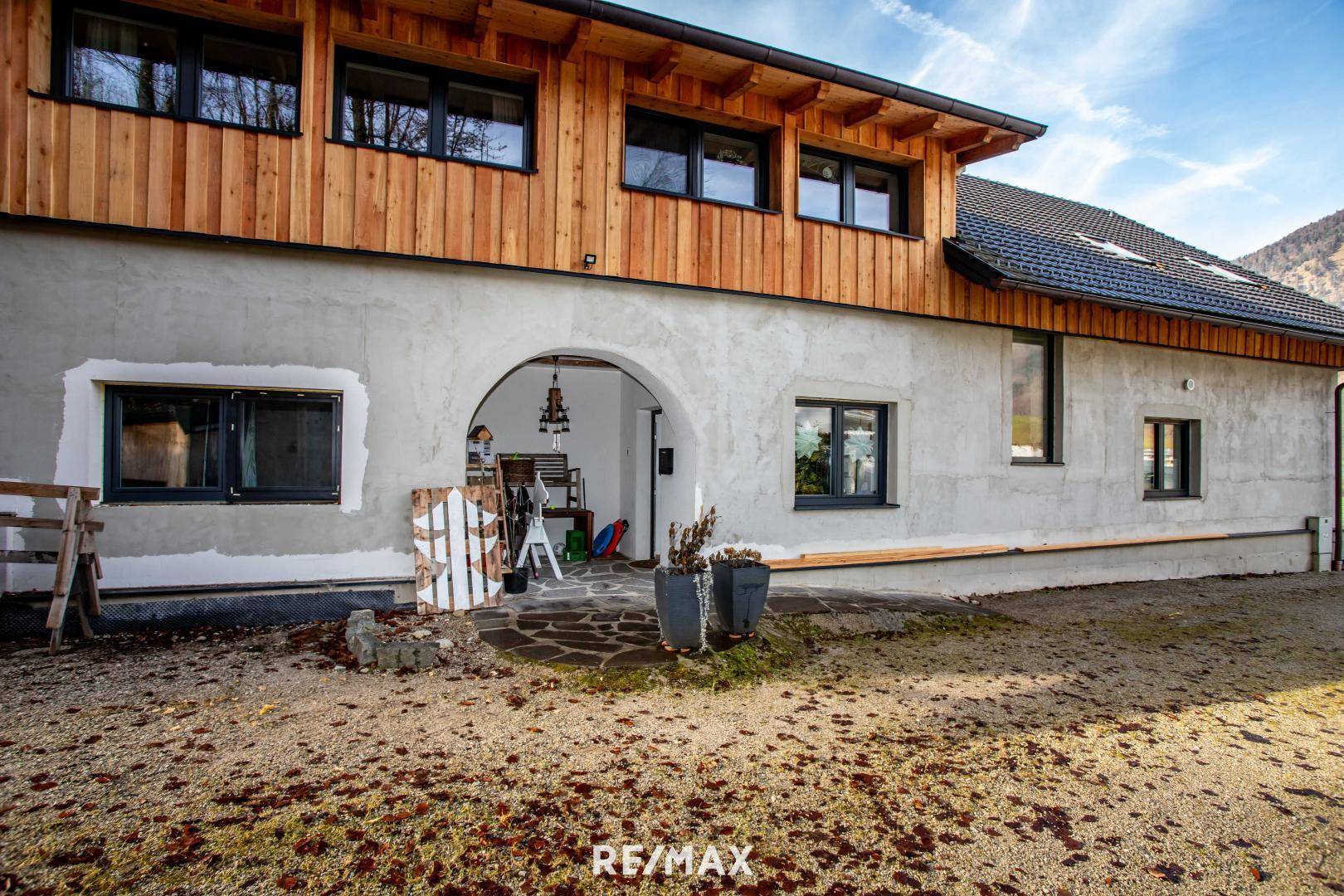 Rustikales Gebäude mit verputzter Fassade und Holzverkleidung im oberen Bereich.