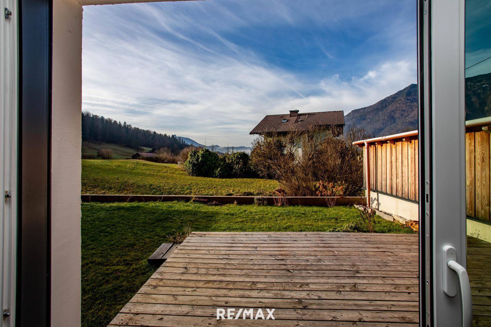 Holzterrasse mit Blick auf den grünen Garten und die umliegende Landschaft.