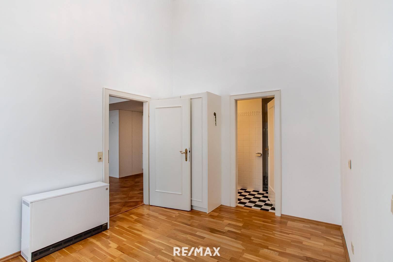 Flur mit Zugang zu verschiedenen Zimmern und einem Badezimmer mit Schachbrettmuster-Fliesen.