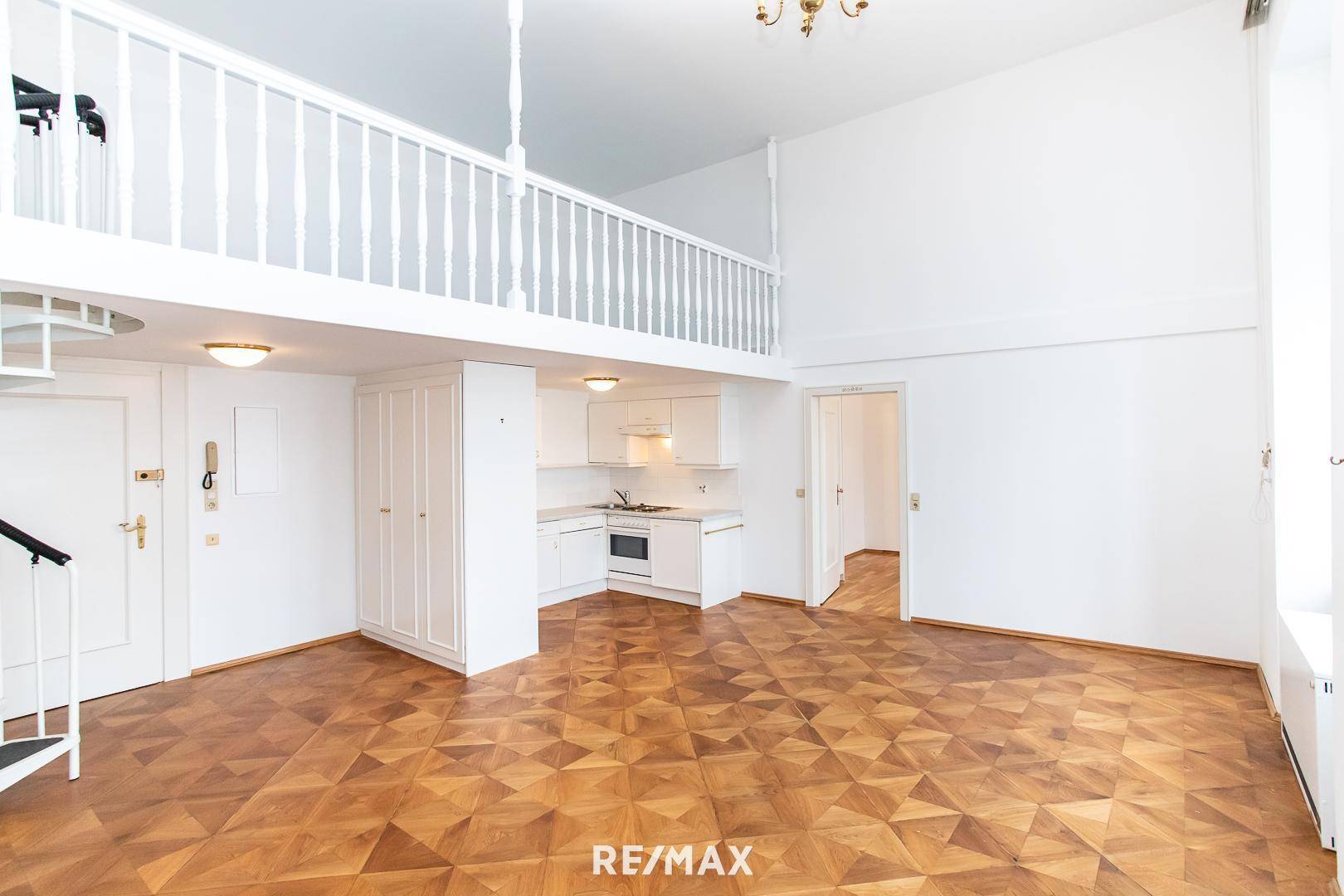 Heller Wohnbereich mit Parkettboden, integrierter Küchenzeile und Zugang zur oberen Galerie.