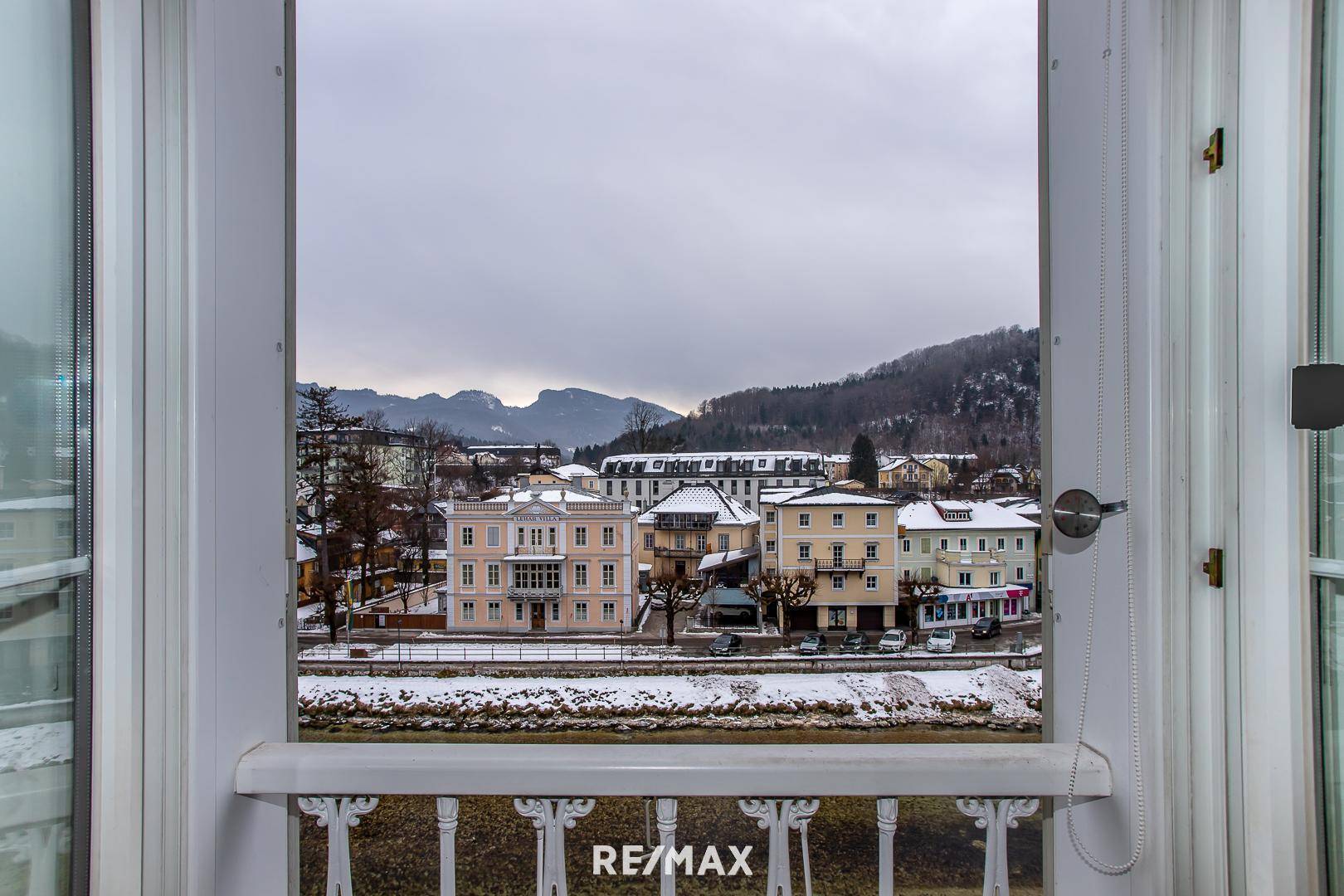 Blick aus dem Fenster auf die verschneite Stadt, den Fluss und die umliegenden Berge.