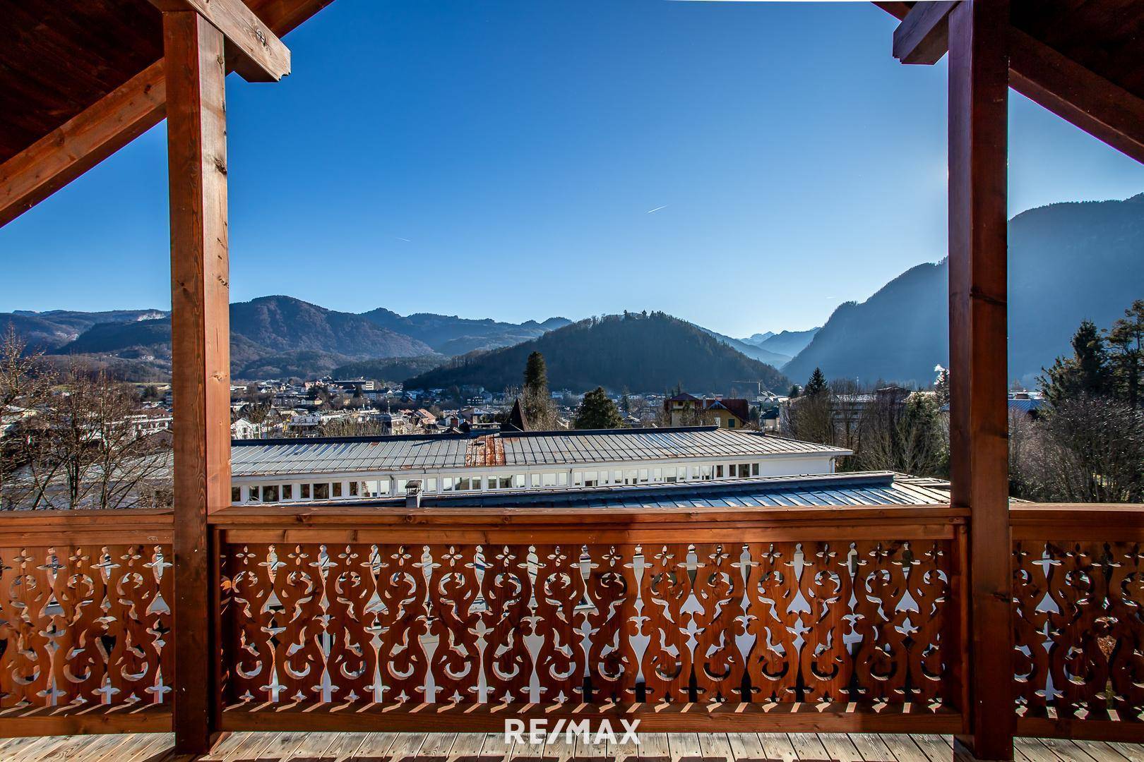 Balkon mit traditionellem Holzgeländer und weitem Blick über die Stadt und Berge.