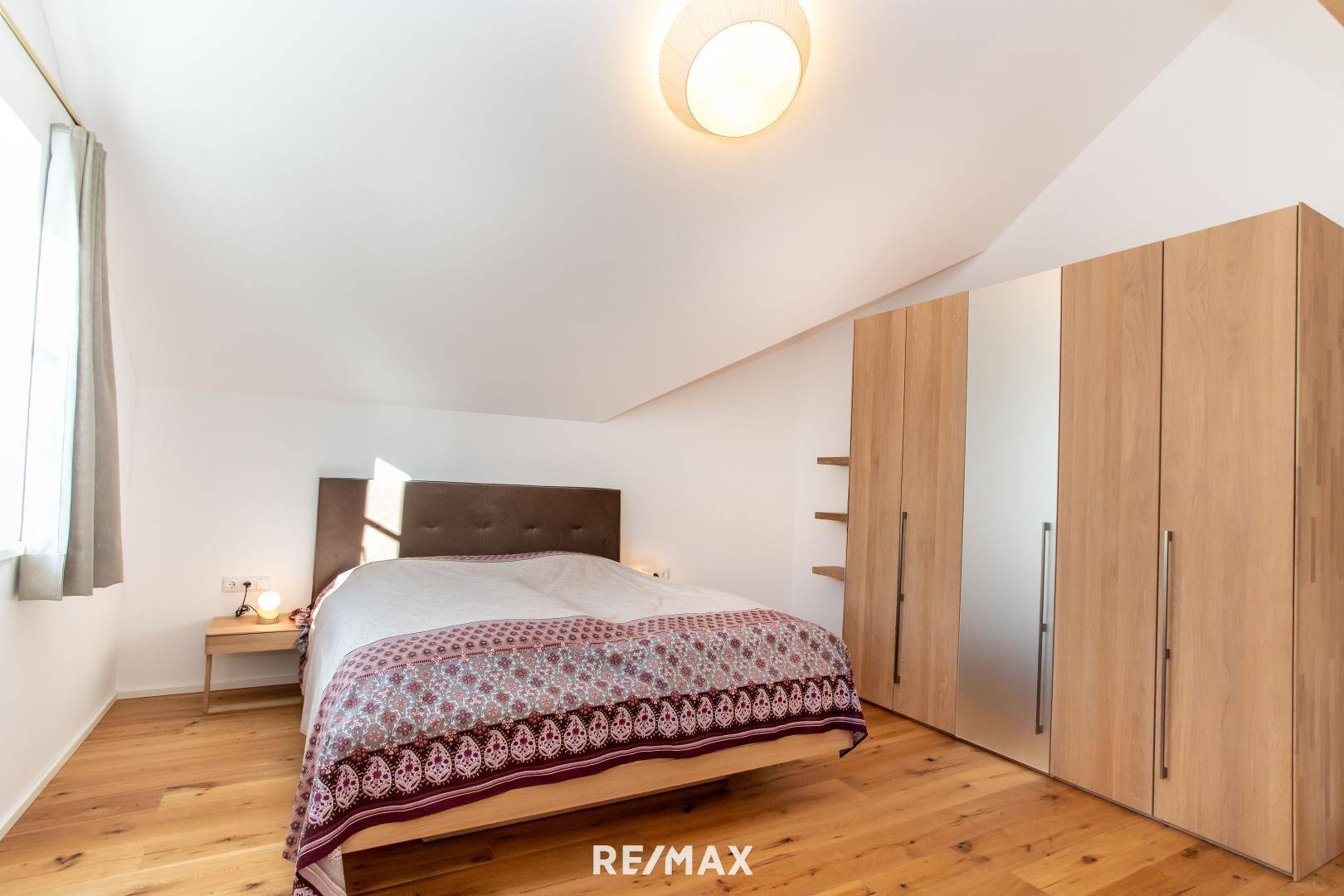 Gemütliches Schlafzimmer mit Holzboden, Einbauschränken und Dachschräge.