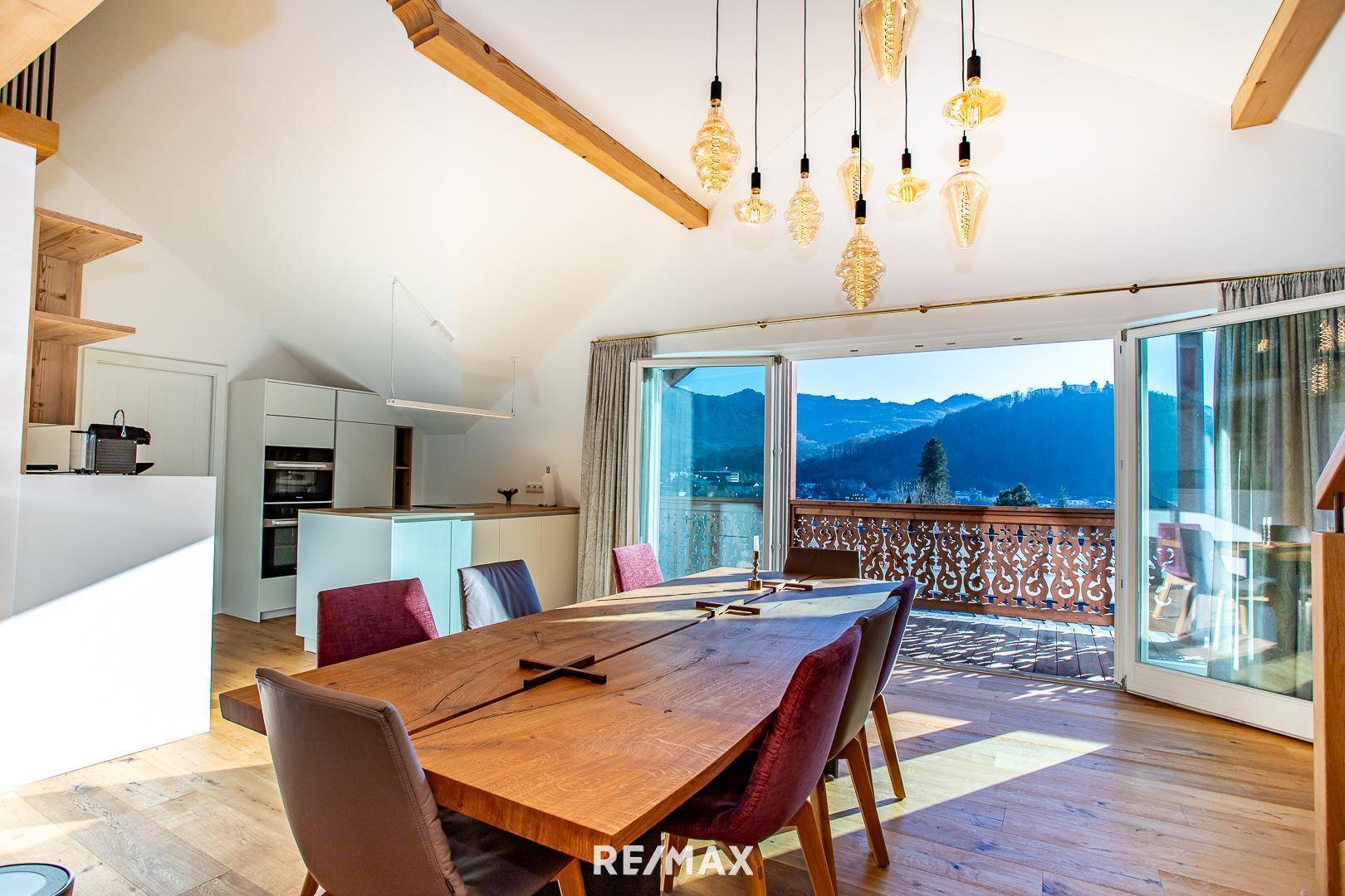 Lichtdurchfluteter Essbereich mit Holztisch und direktem Zugang zum Balkon mit Bergblick.