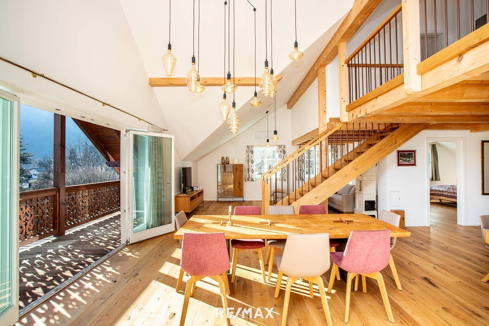 Heller Essbereich mit Holztisch, modernen Pendelleuchten und Bergblick vom Balkon.