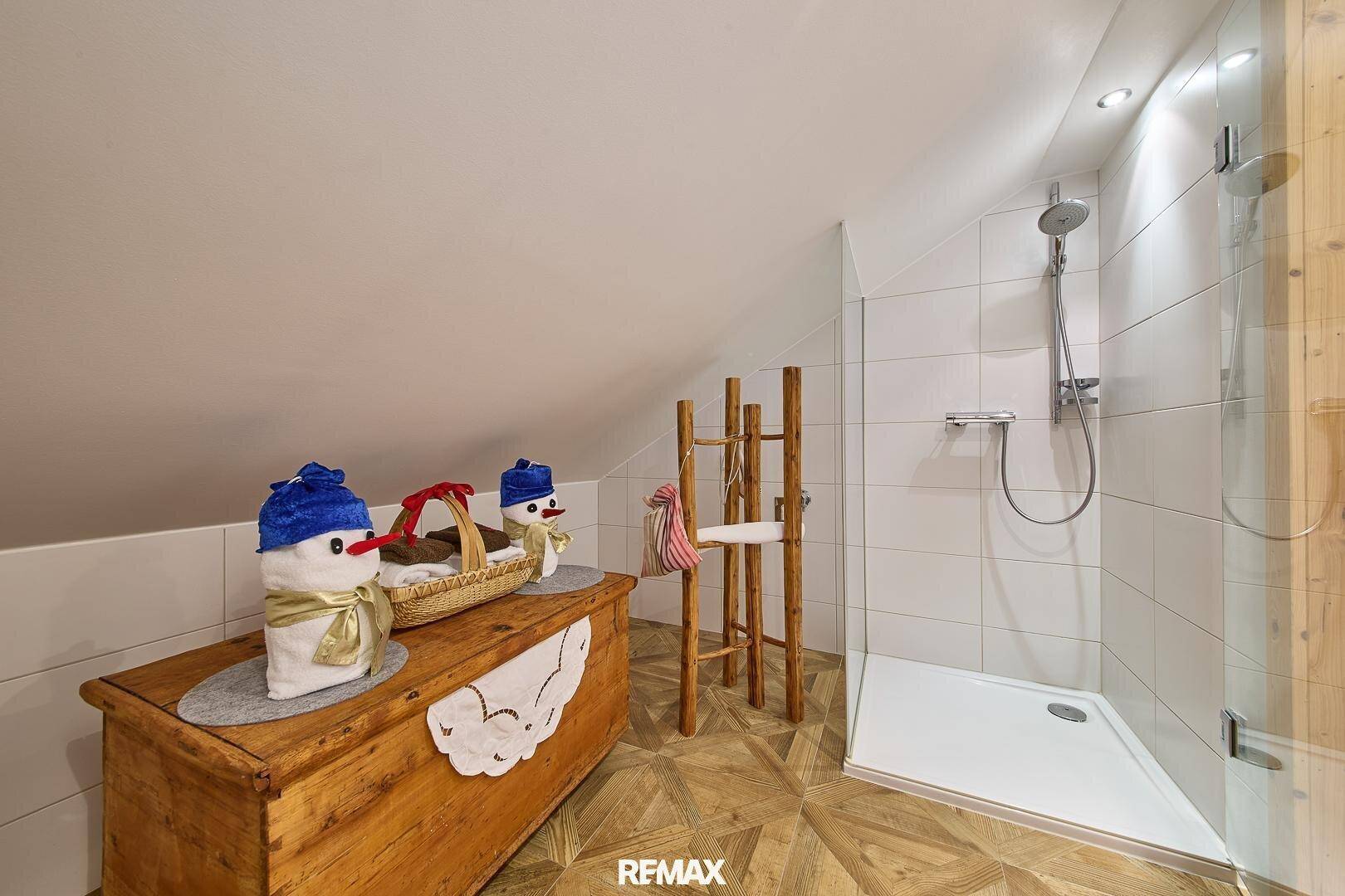 Modernes Badezimmer im Dachgeschoss mit begehbarer Dusche und weiß gefliesten Wänden.
