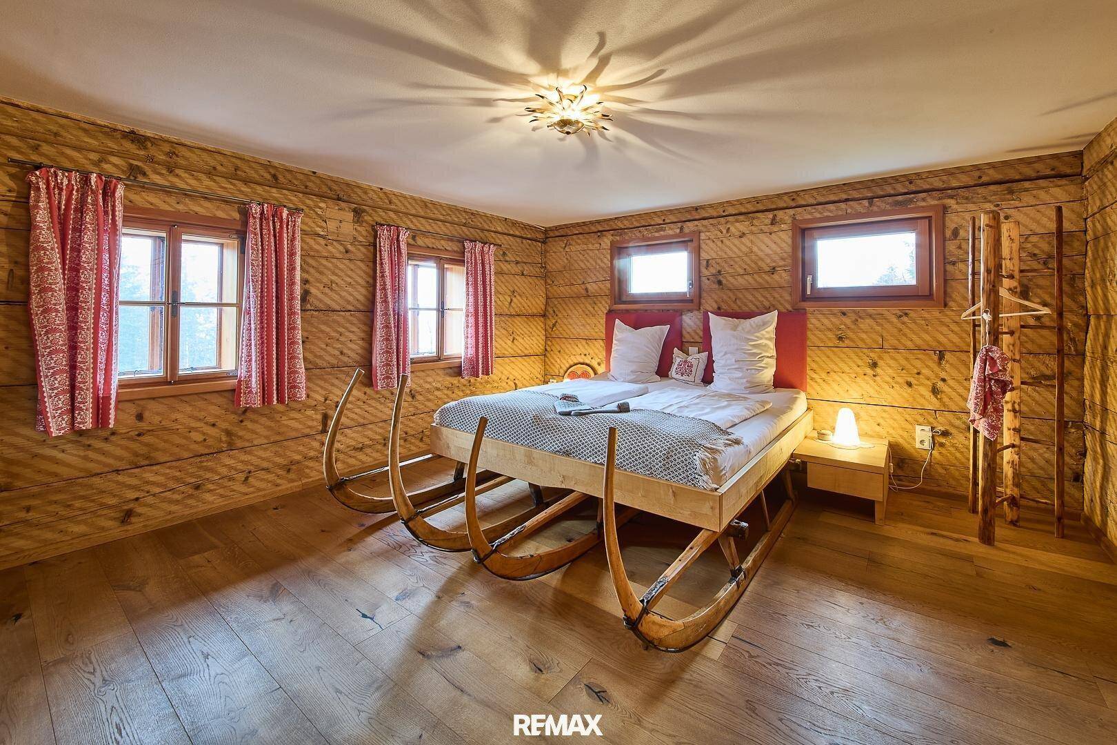 Schlafzimmer im rustikalen Stil mit Holzwänden, Holzboden und einem einzigartigen Bettgestell.