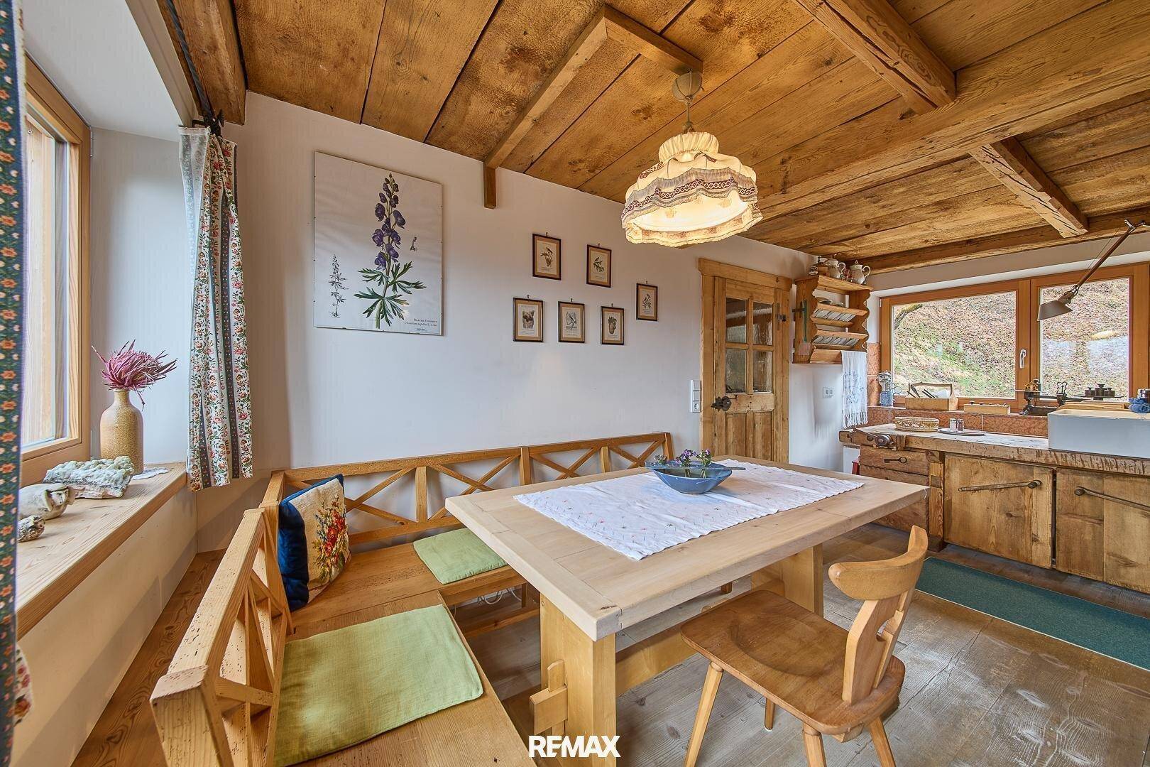 Essbereich mit Holztisch und Eckbank, integriert in eine rustikale Küche mit Holzbalkendecke.