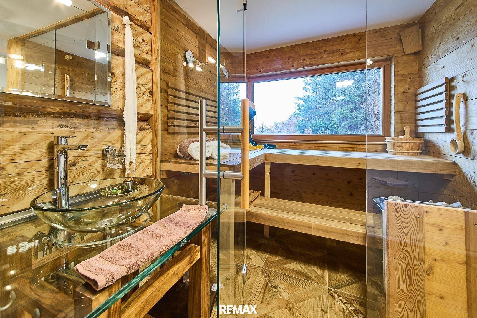 Sauna und Wellnessbereich mit Holzbänken und großem Fenster, integriert in ein modernes Badezimmer.