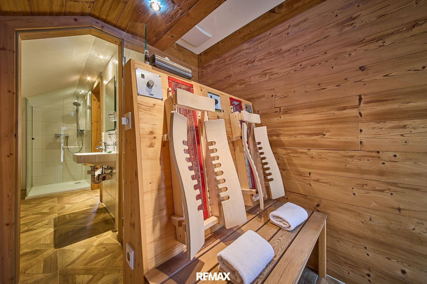 Wellnessbereich mit Infrarotkabine und angrenzendem Badezimmer, alles in Holz gehalten.