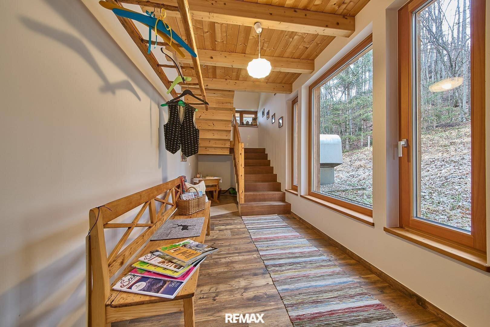 Heller Eingangsbereich im Chalet-Stil mit Holzbank, Garderobe und Treppe zum Obergeschoss.