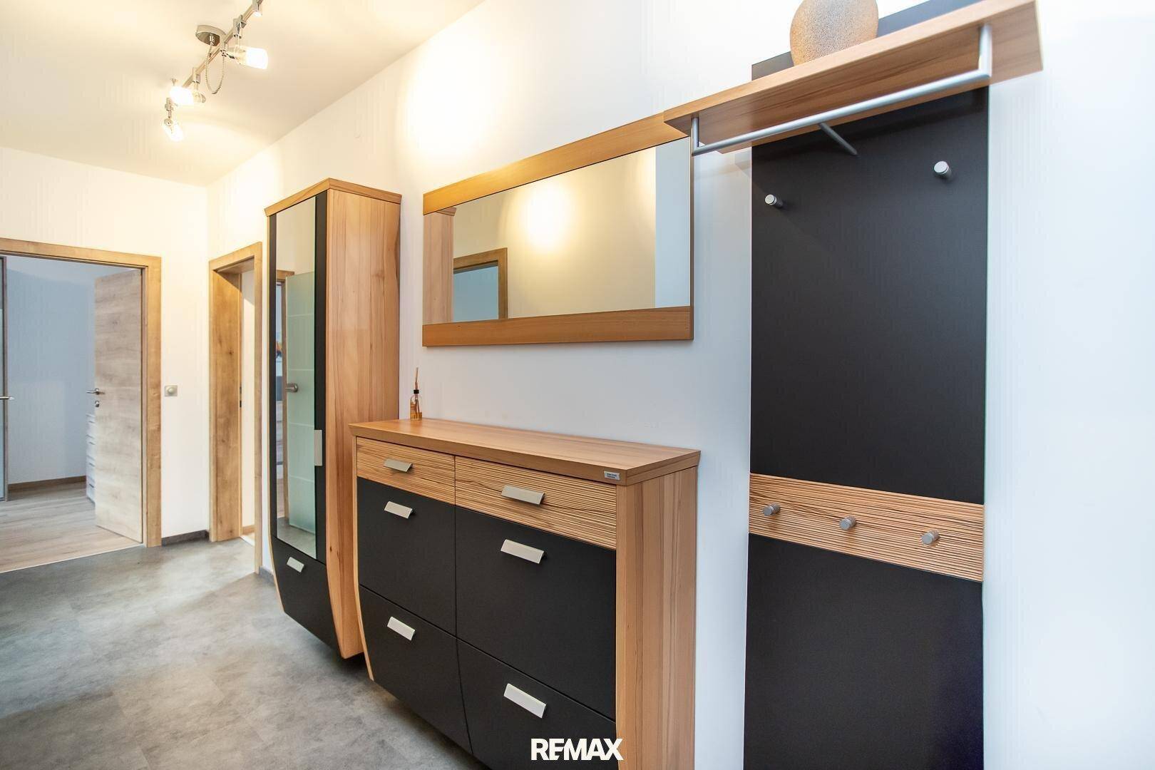 Moderner Eingangsbereich mit dunklem Fliesenboden, Schuhschrank und Garderobe.
