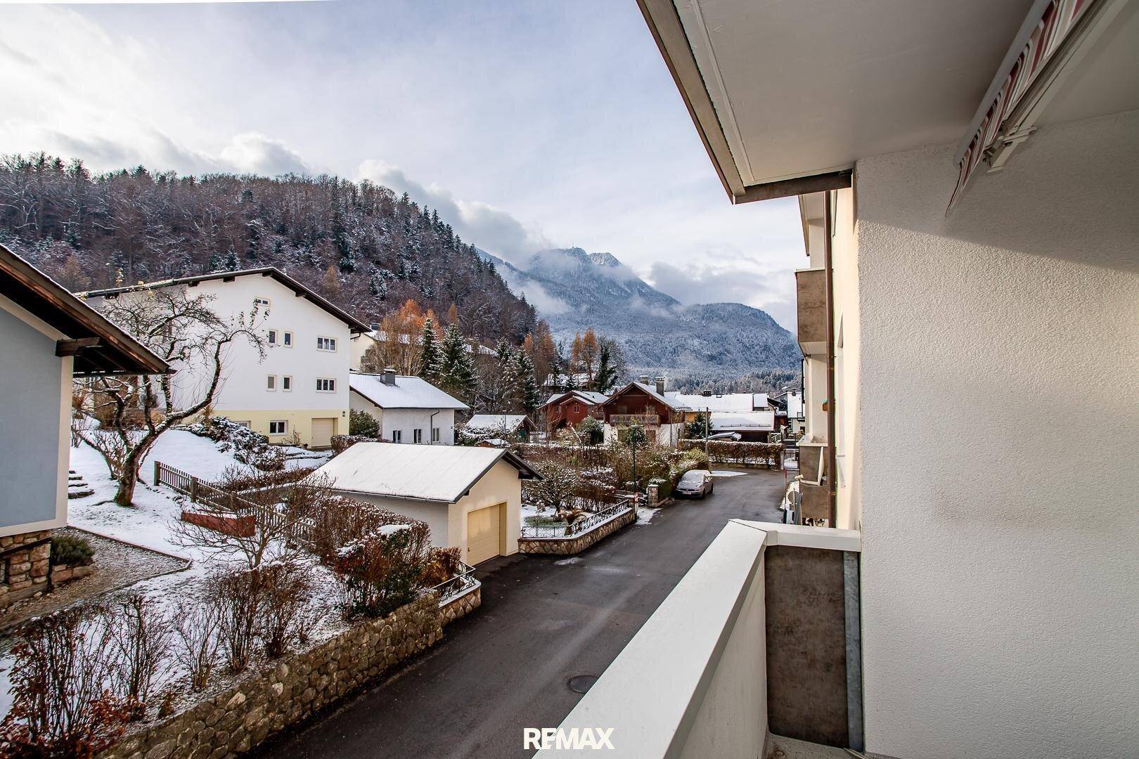 Panoramablick vom Balkon auf eine verschneite Wohngegend mit majestätischen Bergen im Hintergrund.
