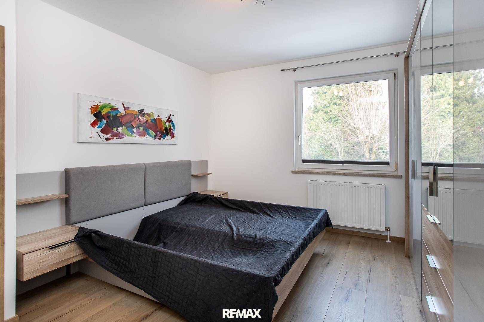 Gemütliches Schlafzimmer mit Holzboden, großem Bett und Spiegelschrank, hell durch das Fenster.