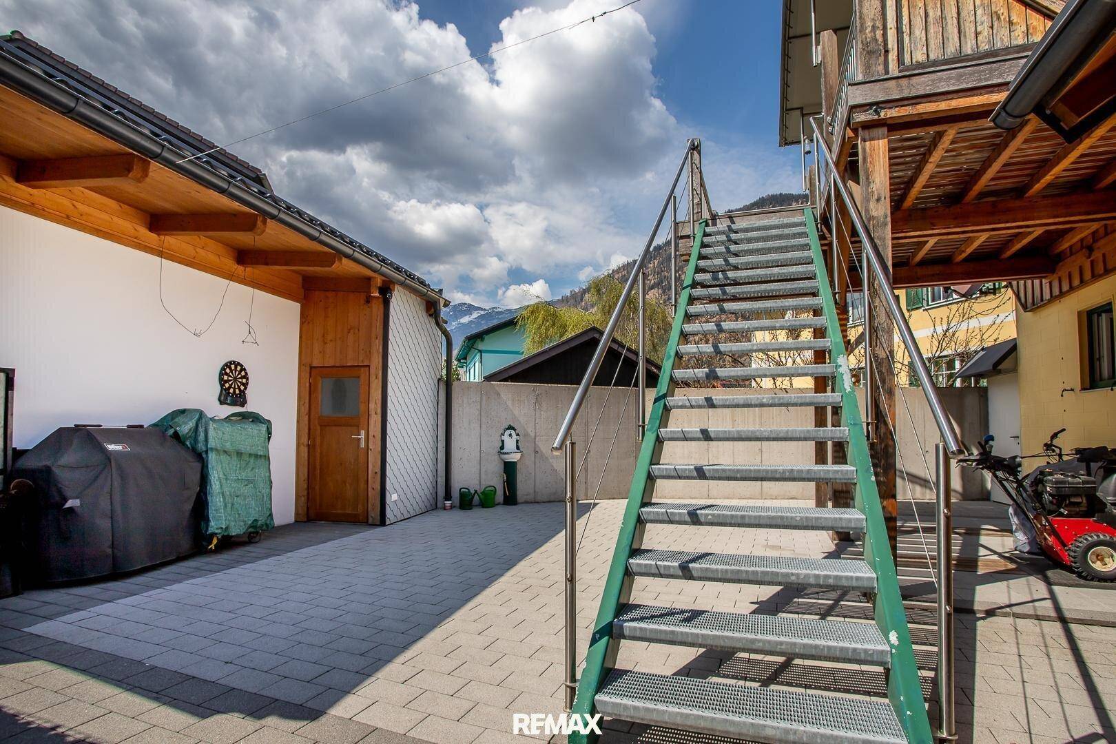 Außenbereich mit Metalltreppe, die zu einem Balkon führt, und gepflastertem Hof.