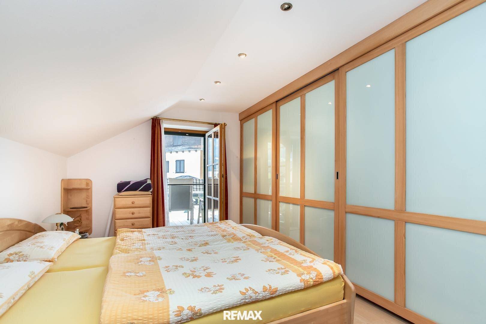 Schlafzimmer mit Holzboden, Einbauschränken und Zugang zu einem Außenbereich.